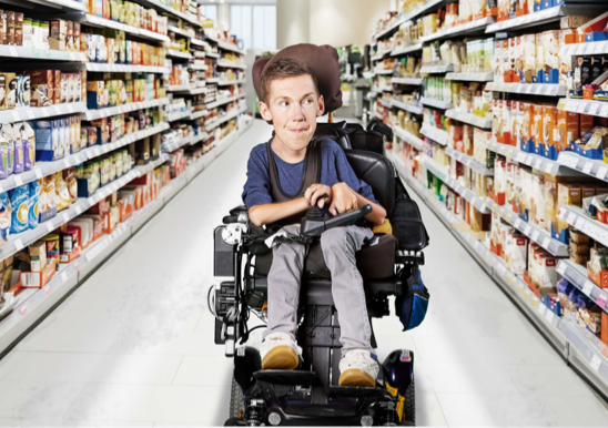 Shane sits in his wheelchair in the middle of a fully stocked supermarket aisle.